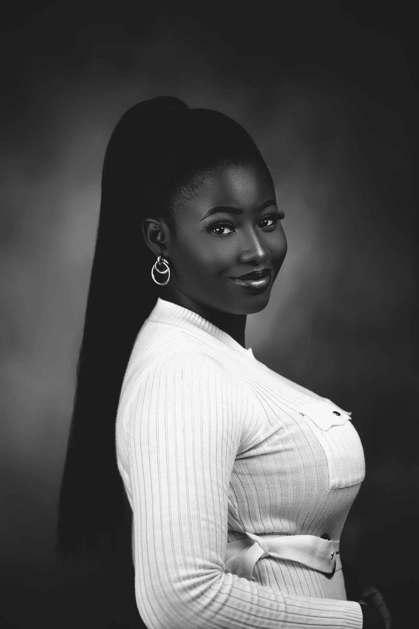 Portrait en noir et blanc d’une femme en haut blanc, le regard tourné vers l’objectif.